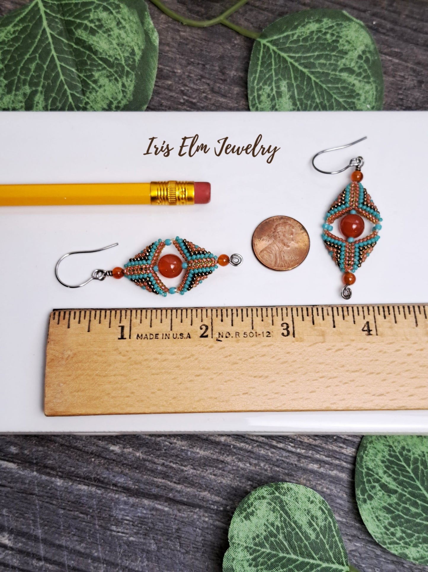 2 and 3/8 inch long Beaded earrings on a ruler with 'Iris Elm Jewelry' branding, surrounded by green leaves.