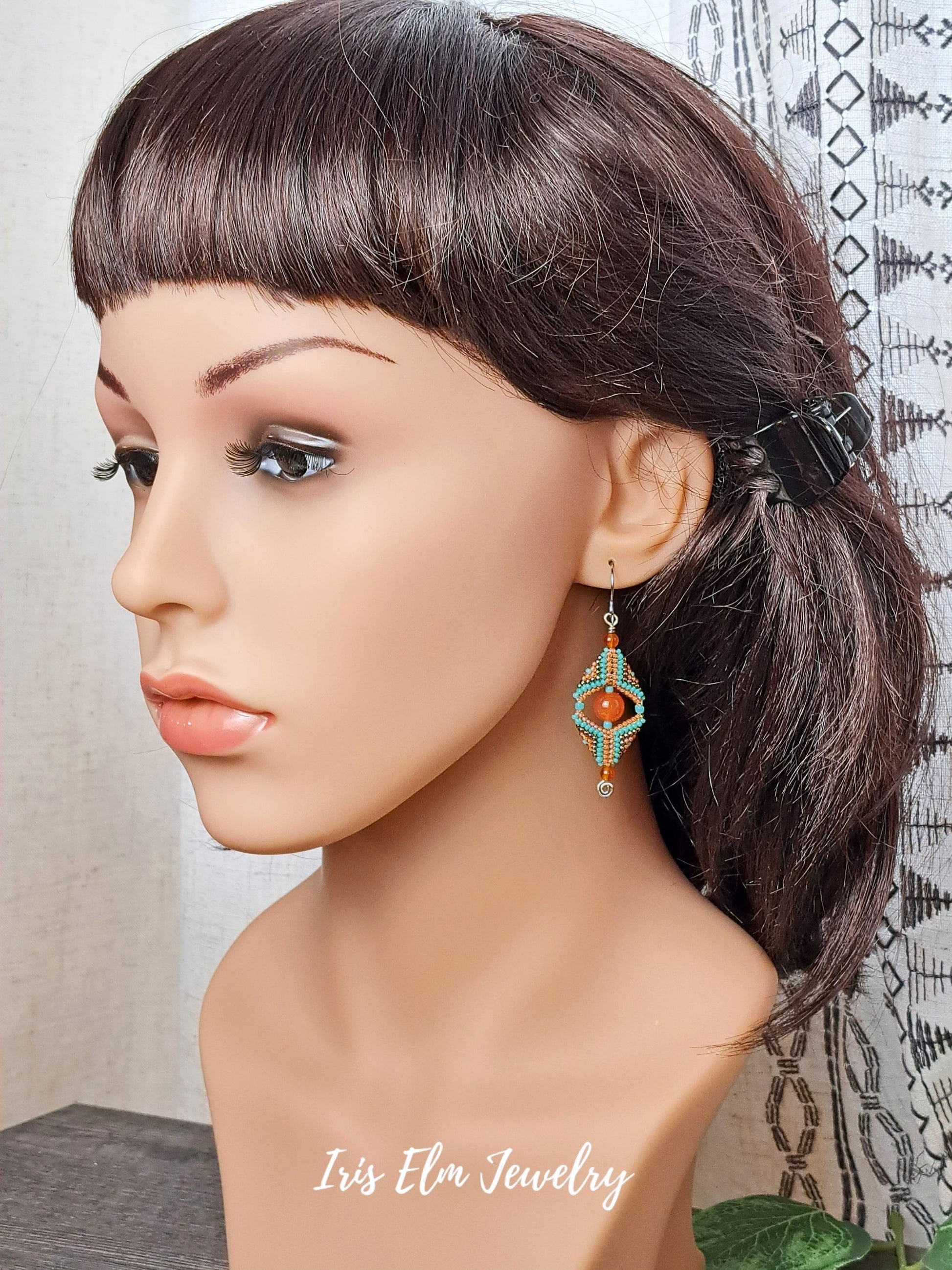 Mannequin head with a ponytail and decorative carnelian gemstone and seed bead beadwork earrings, featuring 'Iris Elm Jewelry'.