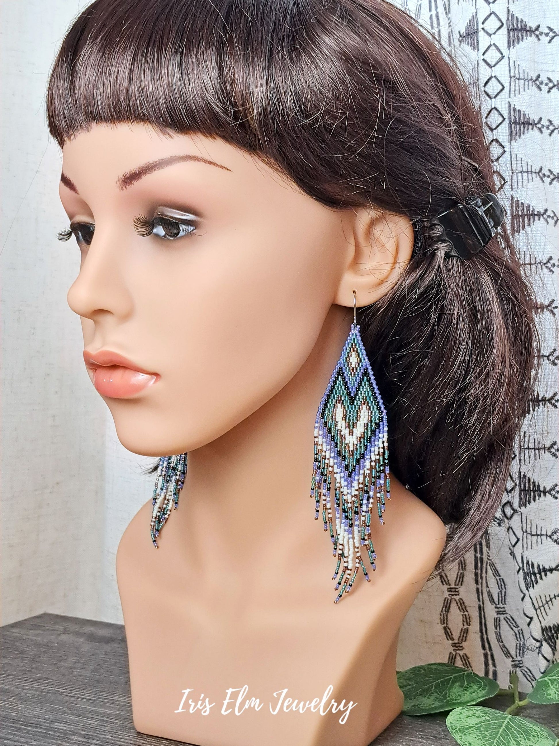 Mannequin head with long purple, teal, black, and white seed bead heart fringe beaded earrings and 'Iris Elm Jewelry' branding.