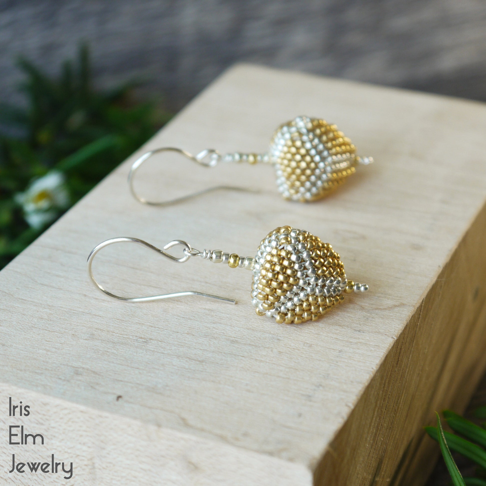 Gold and silver glass beaded triangle earrings on a wooden block with 'Iris Elm Jewelry' branding.