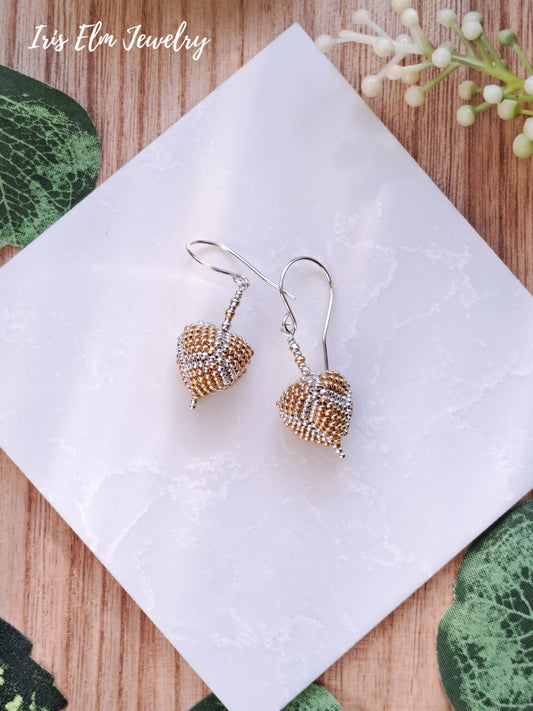 Pair of beaded gold and silver seed bead triangle-shaped earrings on a white napkin with 'Iris Elm Jewelry' branding.