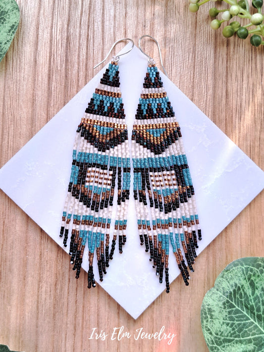 Beaded boho seed bead fringe earrings on a white card with 'Iris Elm Jewelry' branding, placed on a wooden surface.