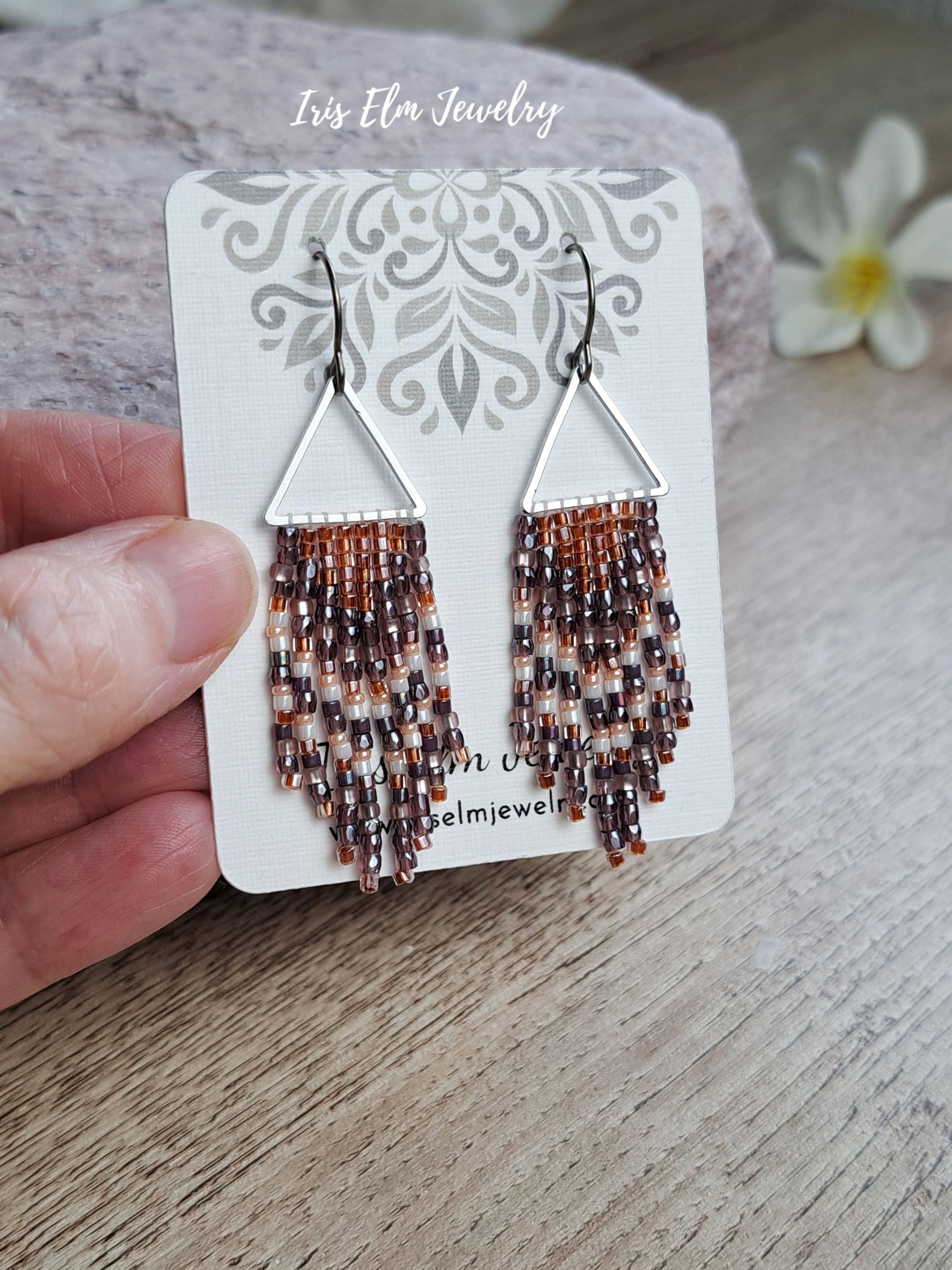 handmade small seed bead handwoven purple and copper orange seed bead fringe earrings on an earring card with Iris Elm Jewelry branding.