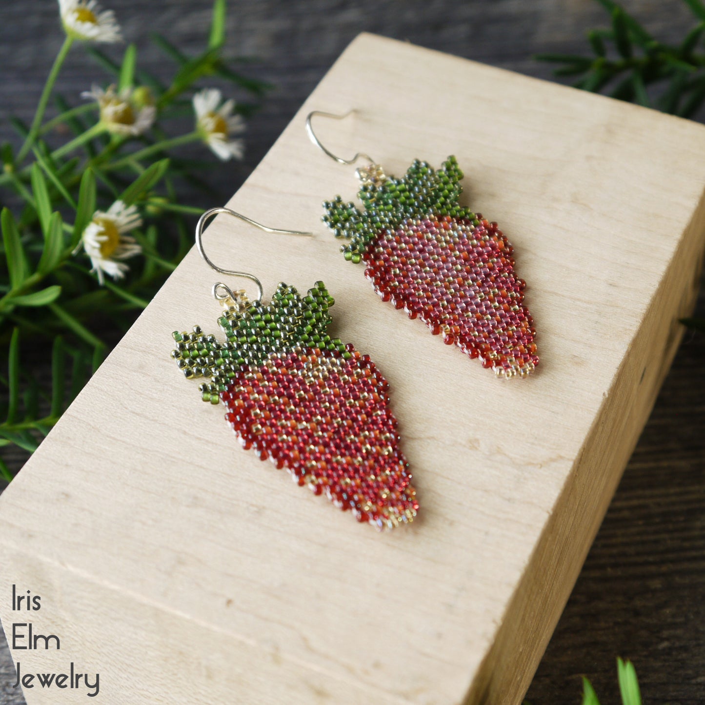 handmade woven Strawberry-shaped earrings on a wooden block with a natural background
