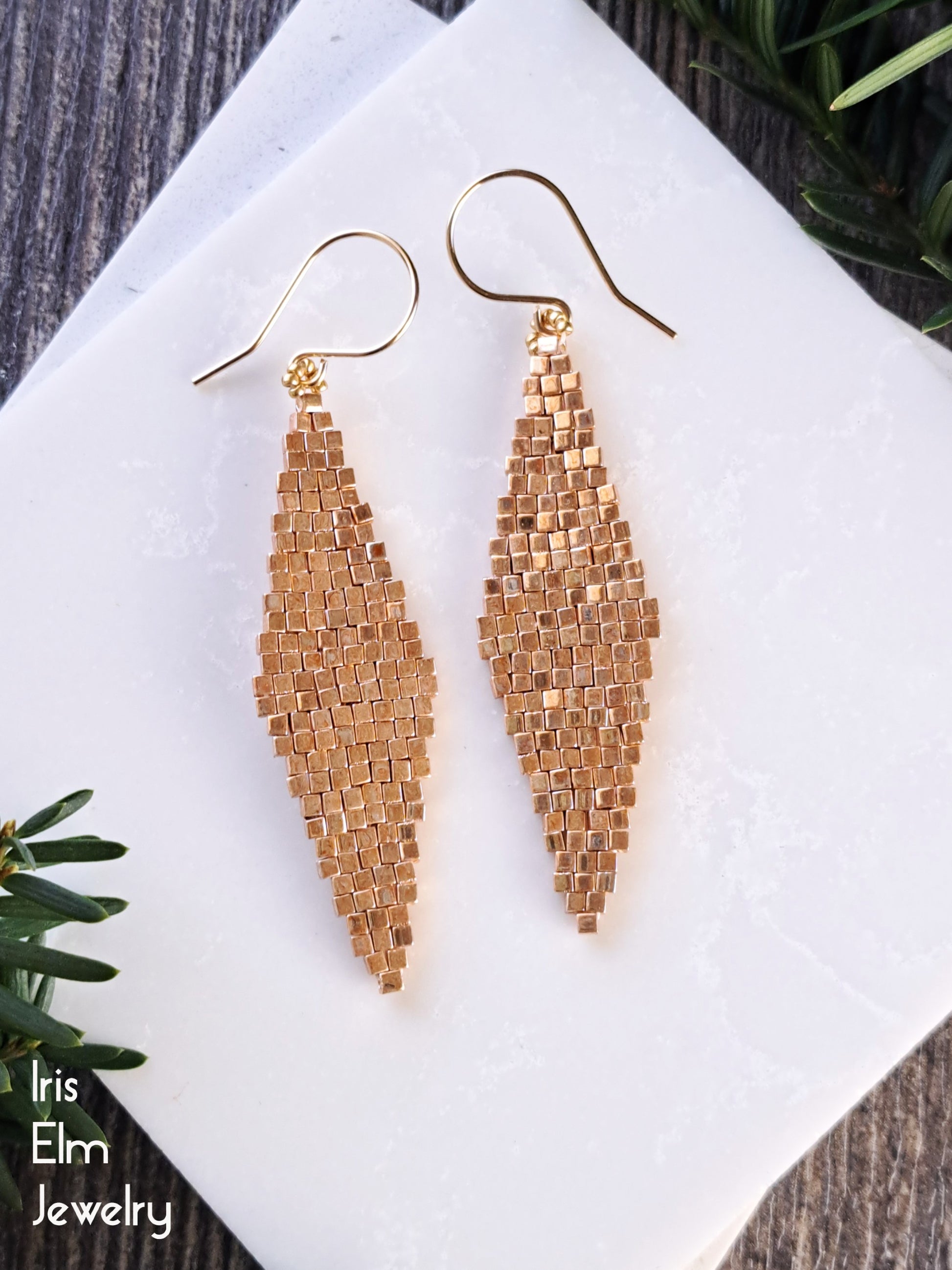 Pair of gold beaded diamond shape glass earrings with goldfilled ear wires on a white surface with 'Iris Elm Jewelry' branding.