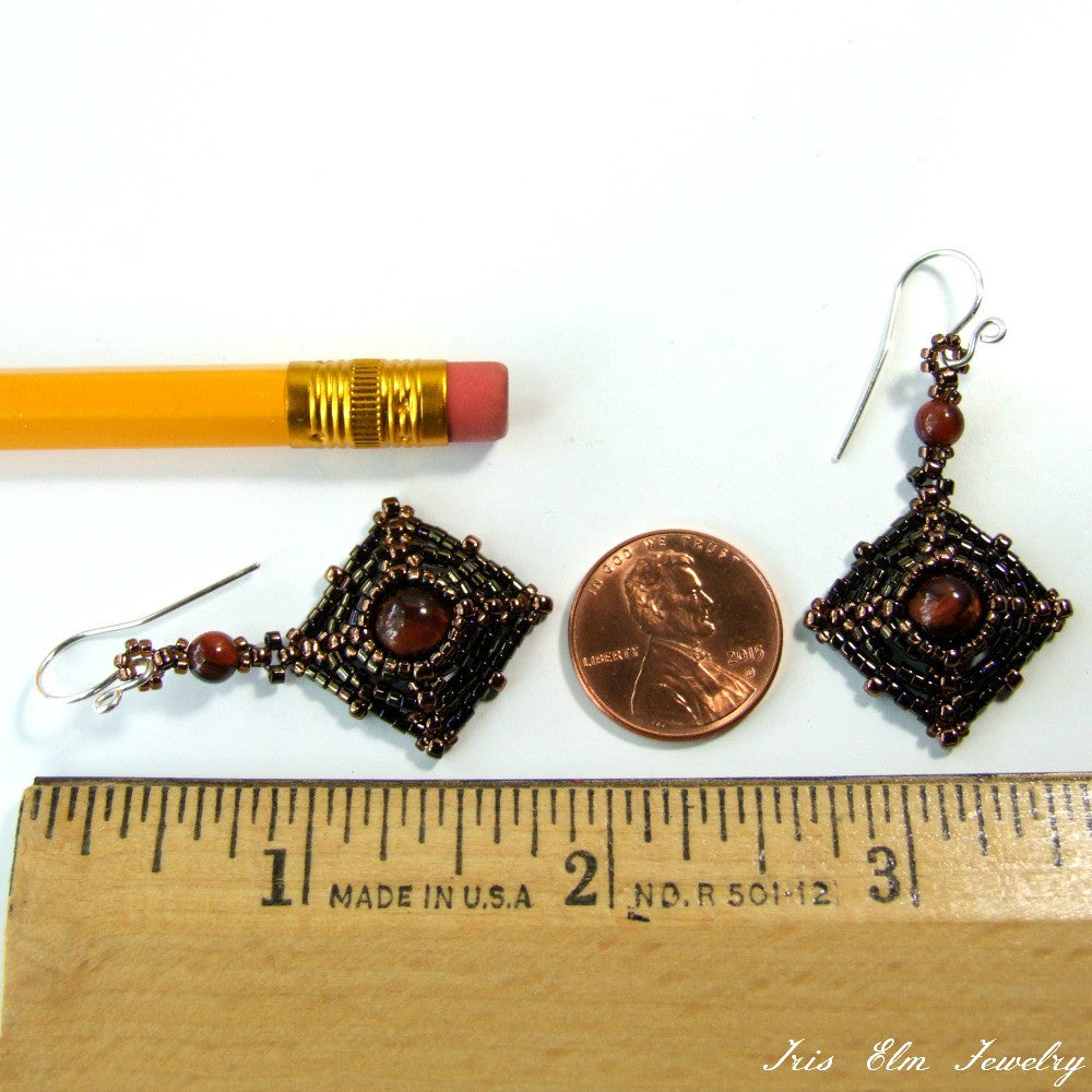 Pair of earrings with brown beads next to a pencil and penny for scale, on a white background.