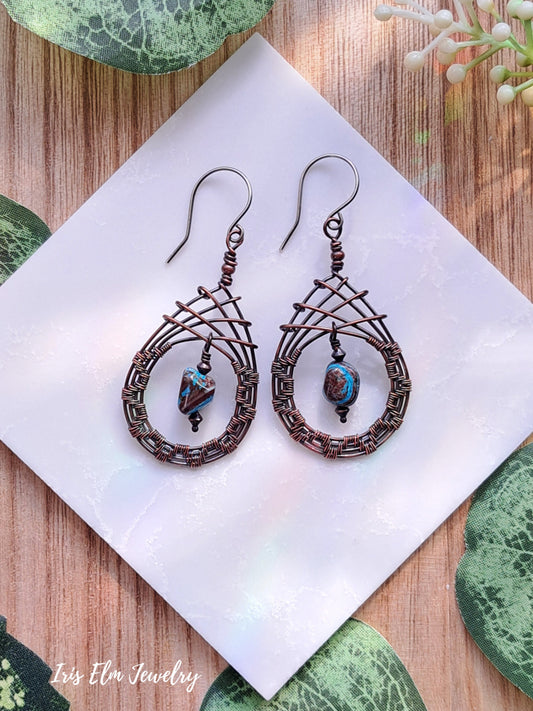 Pair of copper wire-wrapped blue sky jasper teardrop earrings with beads on a white napkin.