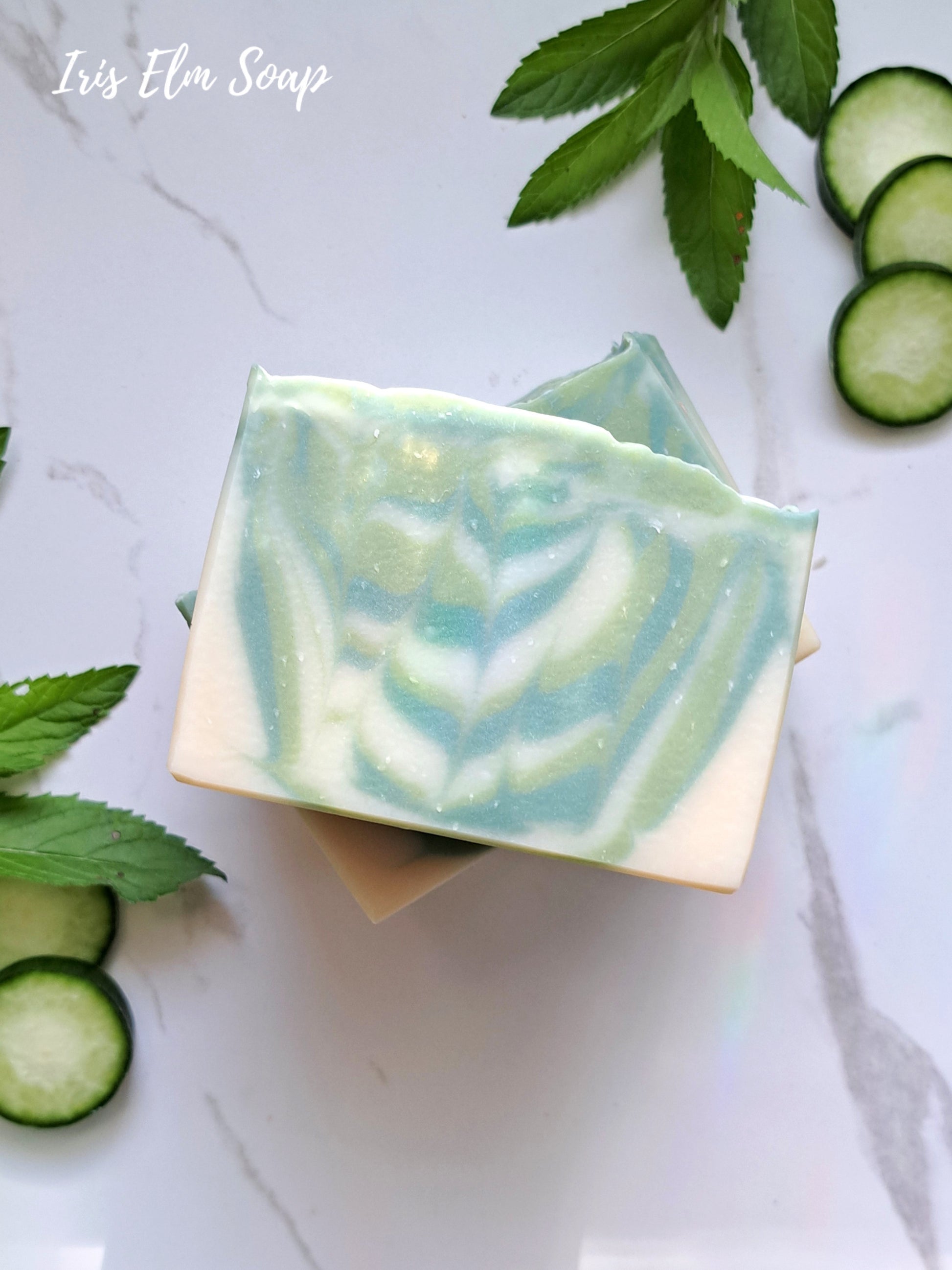 Green and white striped garden mint and cucumber handmade soap bar with cucumber slices and leaves on a light background