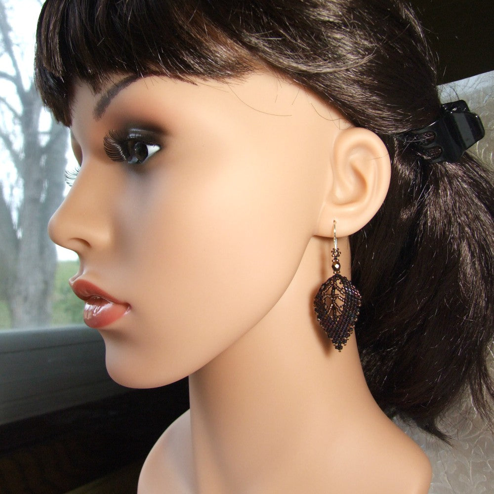 Mannequin head with dark hair and a decorative brown leaf earring