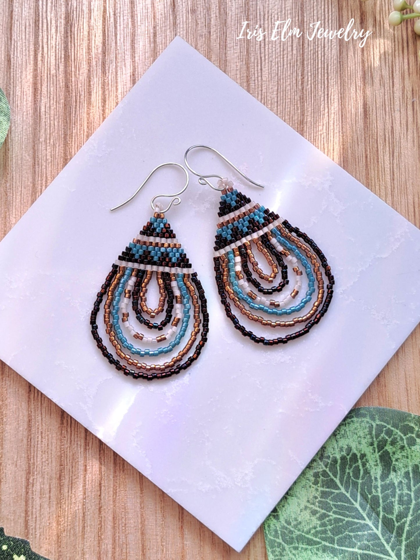 Pair of beaded seed bead teardrop brown and aqua earrings on a white card with 'Iris Elm Jewelry' branding.