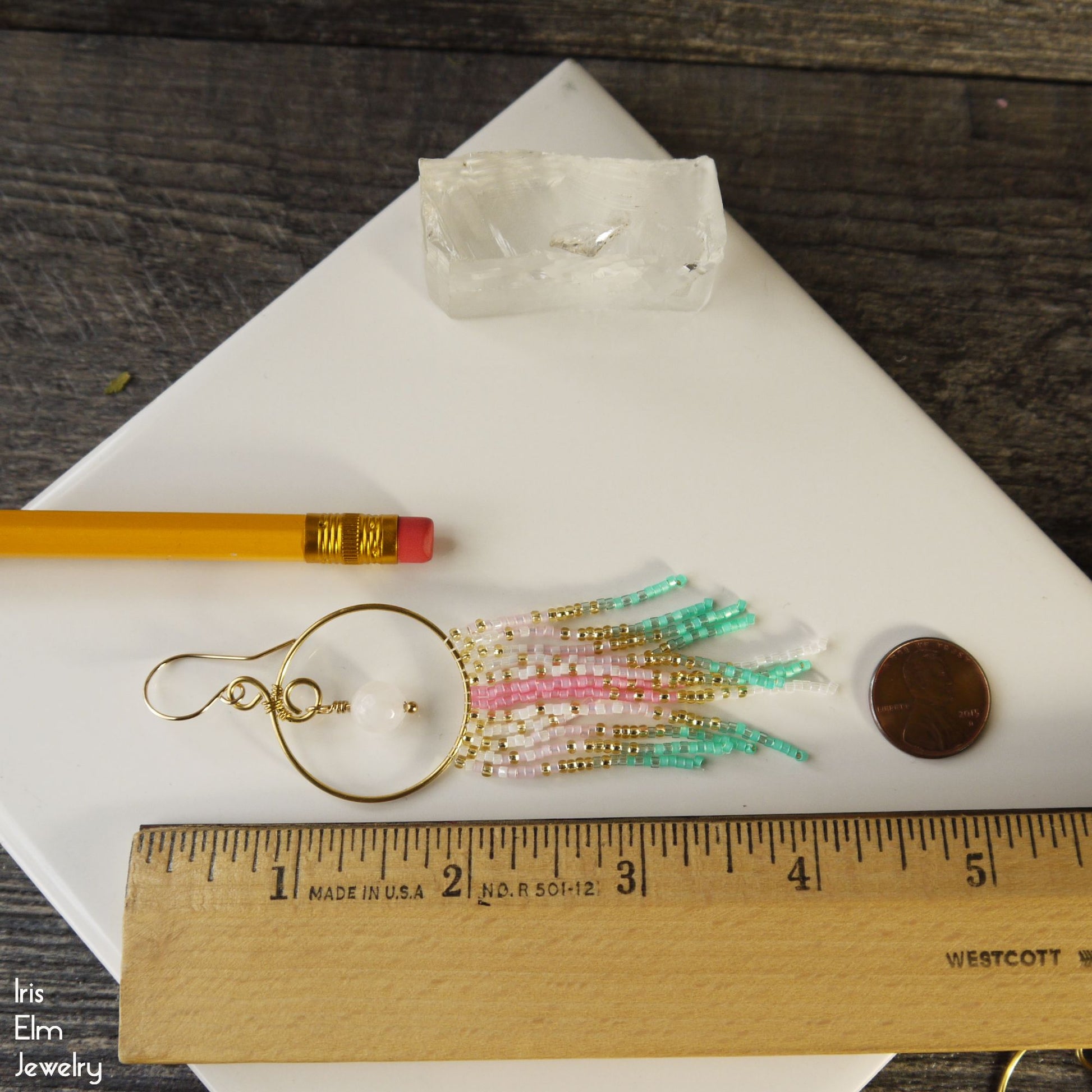 4.25 inch long fringe earrings with colorful beads on a white surface, ruler for scale, pencil, and coin.