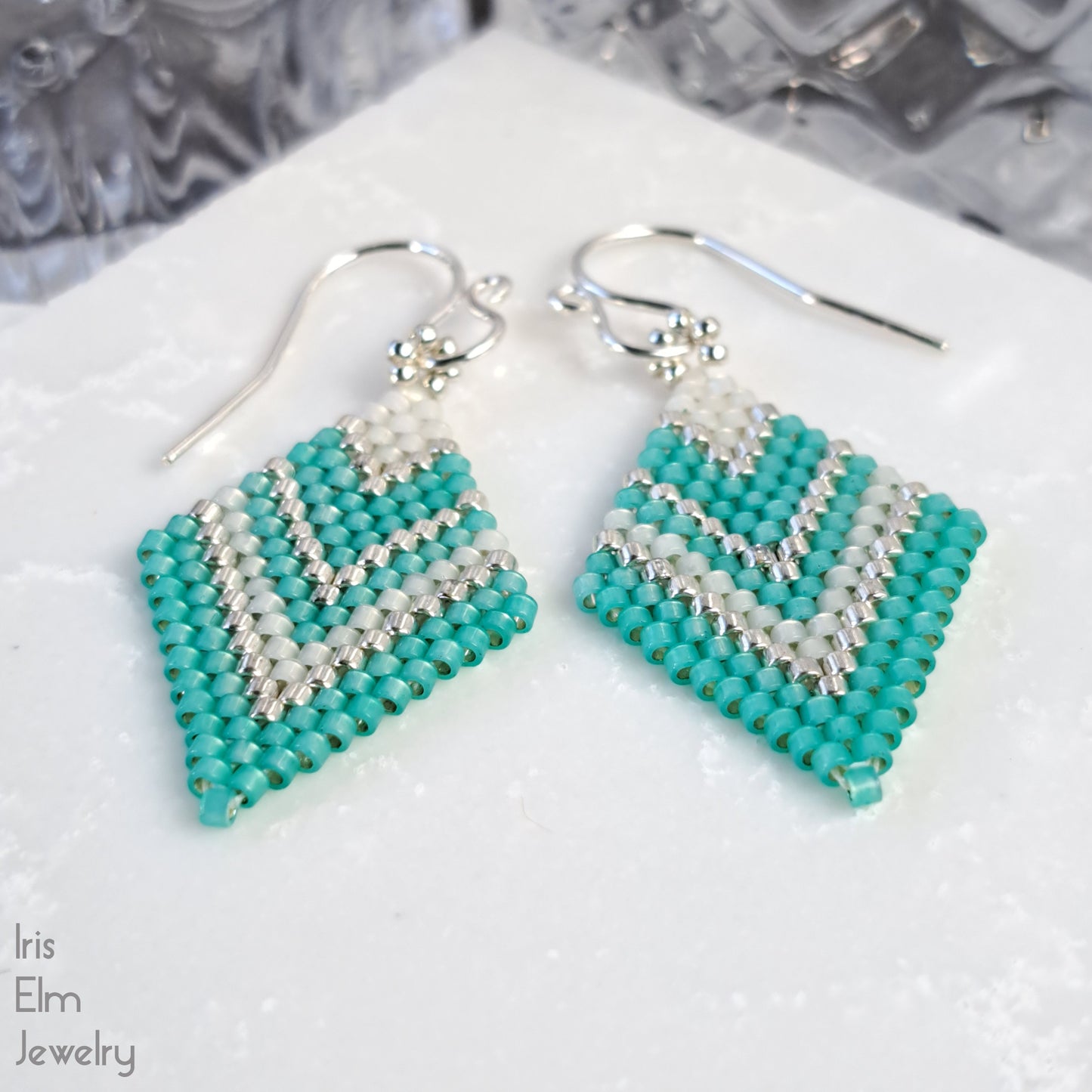 handmade mint green and silver beaded seed bead brick stitch earrings on a white surface with 'Iris Elm Jewelry' branding.