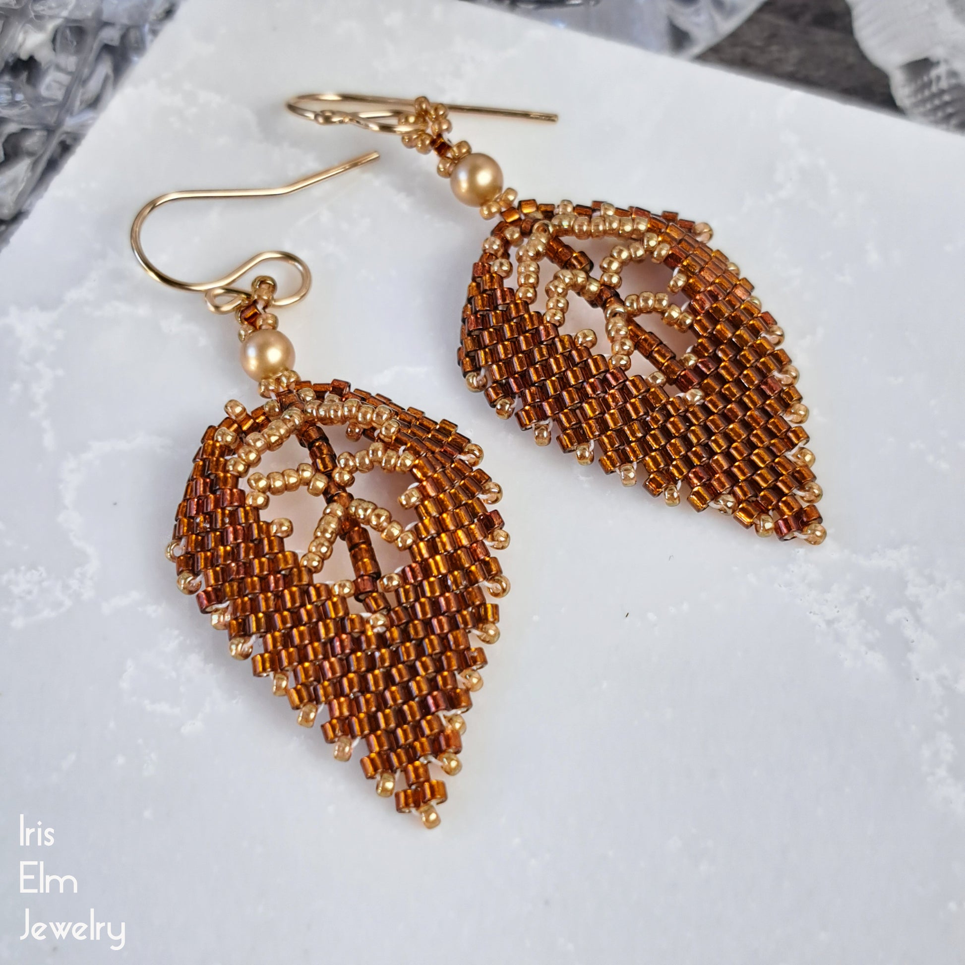 Autumn Leaf-shaped beaded handcrafted earrings on a white surface with 'Iris Elm Jewelry' branding.