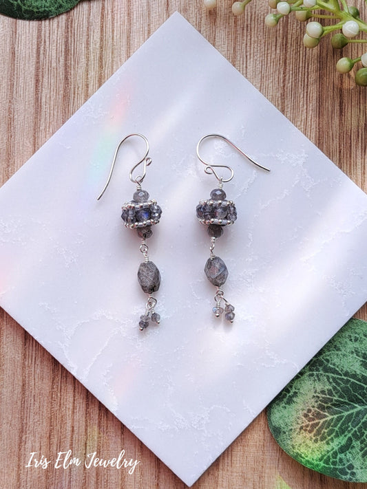 Pair of silver sterling silver beadwork earrings with labradorite stone beads on a white tile.