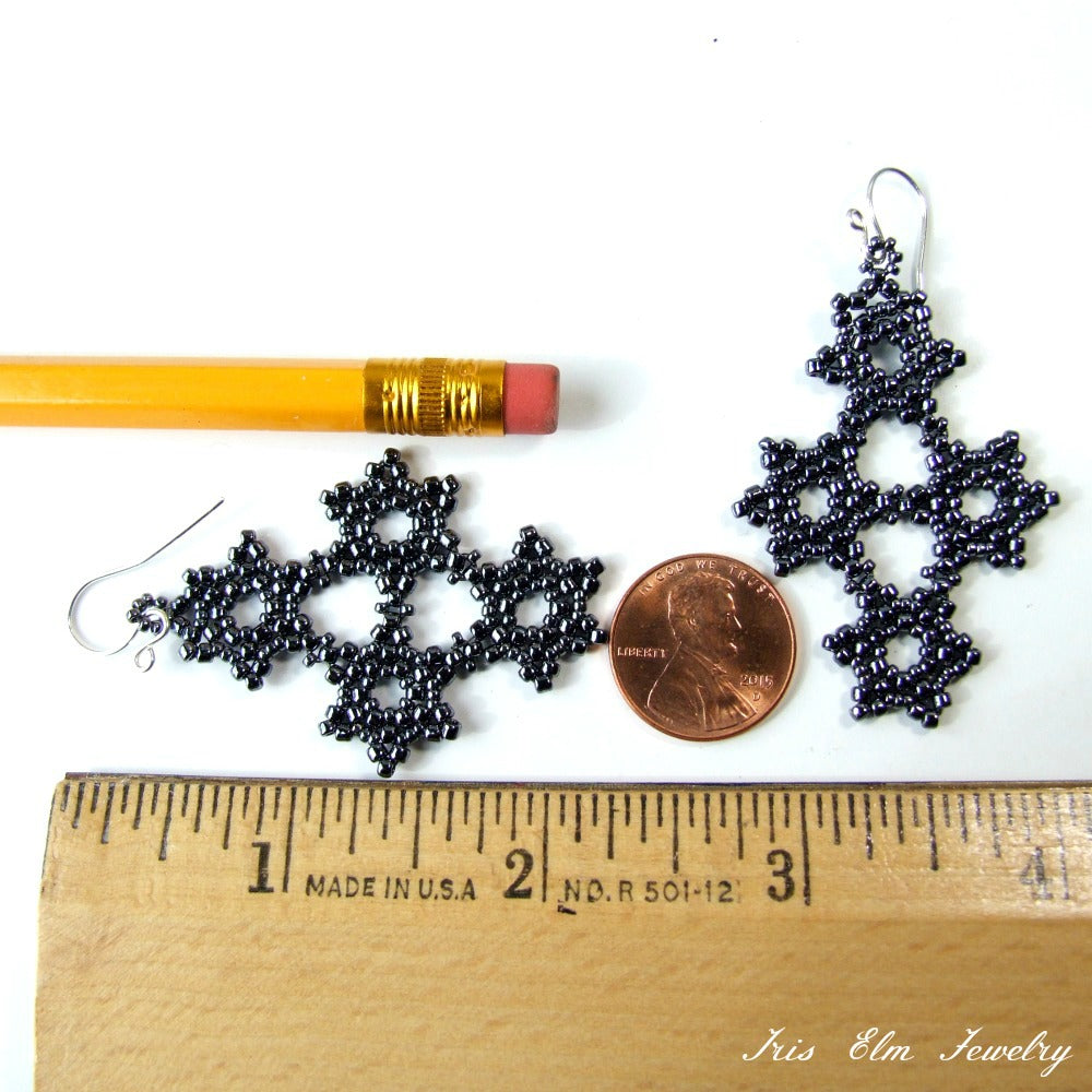 Pewter grey handmade beaded earrings next to a pencil, penny, and ruler for scale on a white background