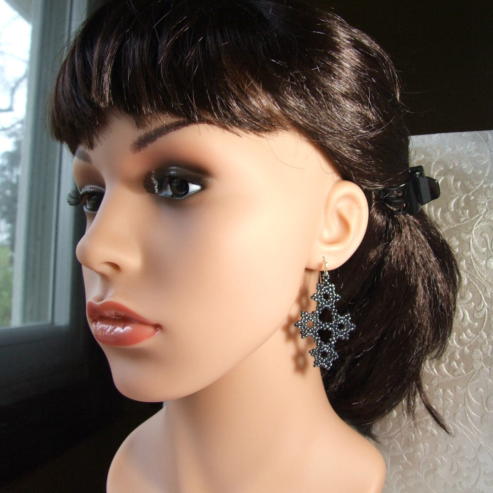 Mannequin head with dark hair styled in a ponytail, wearing a decorative earring.