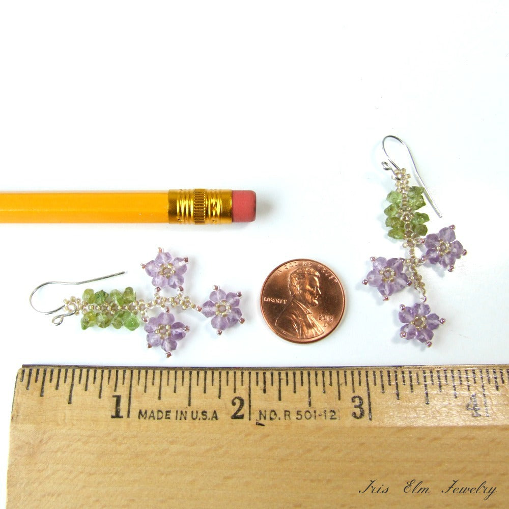 Pair of floral earrings with a penny and pencil for scale on a white background