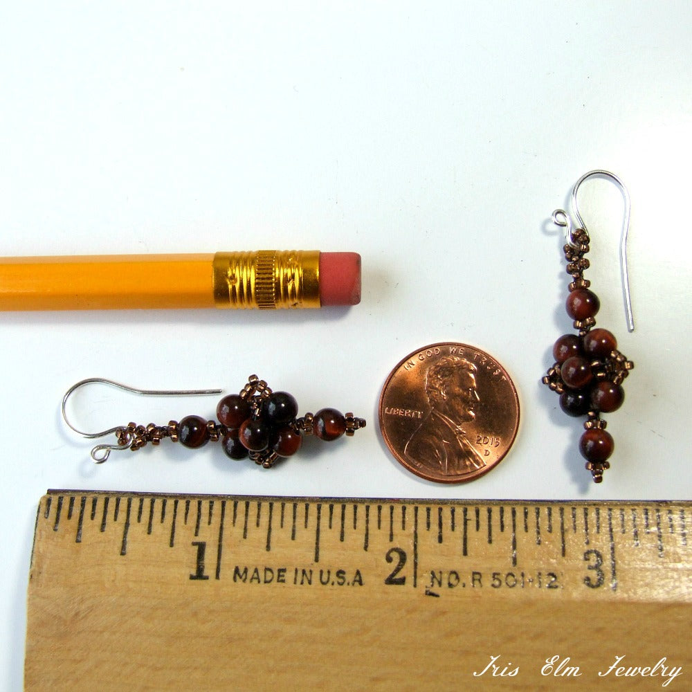 Pair of beaded gemstone brown earrings next to a penny and a ruler for scale on a white background
