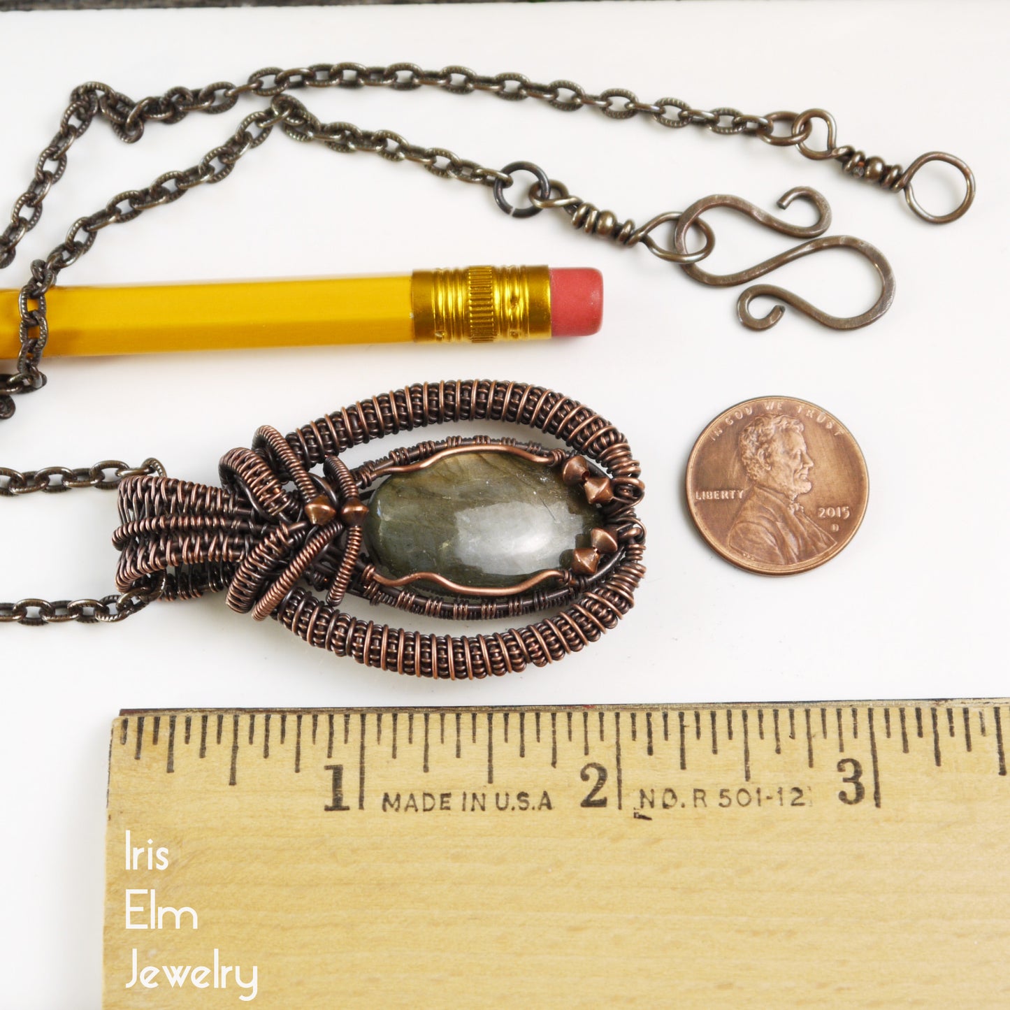 Jewelry necklace with 2 and 1/8 inch pendant next to a pencil and penny for scale, on a white background with 'Iris Elm Jewelry' branding.