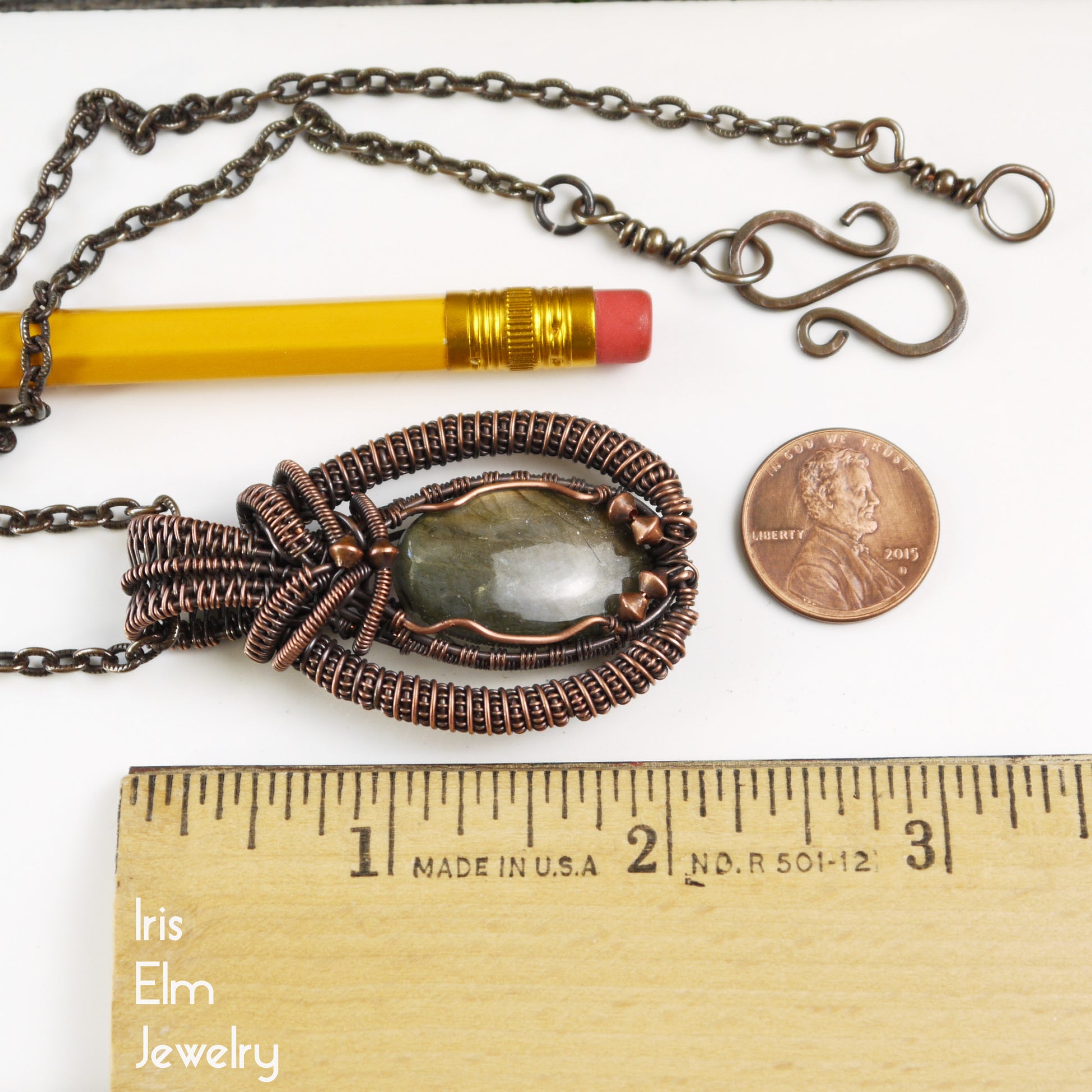 Jewelry necklace with 2 and 1/8 inch pendant next to a pencil and penny for scale, on a white background with 'Iris Elm Jewelry' branding.