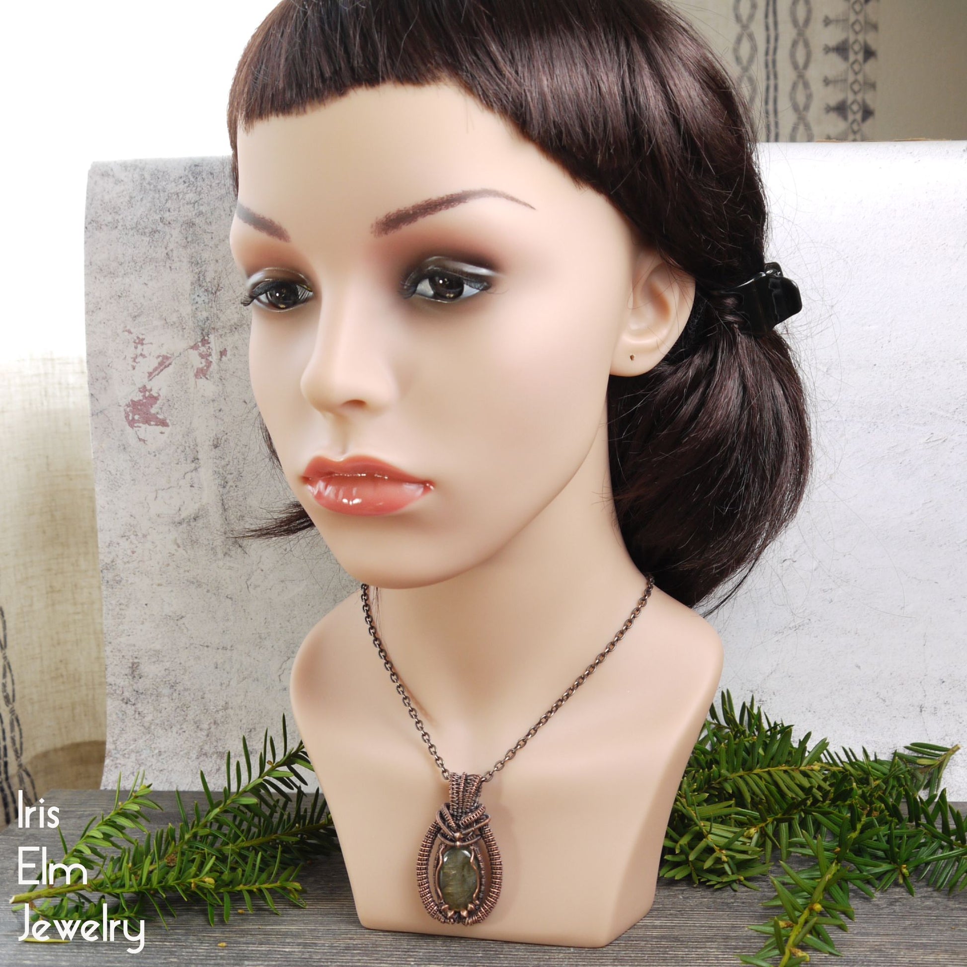 Mannequin head with a copper wire wrapped labradorite pendant necklace on a neutral background