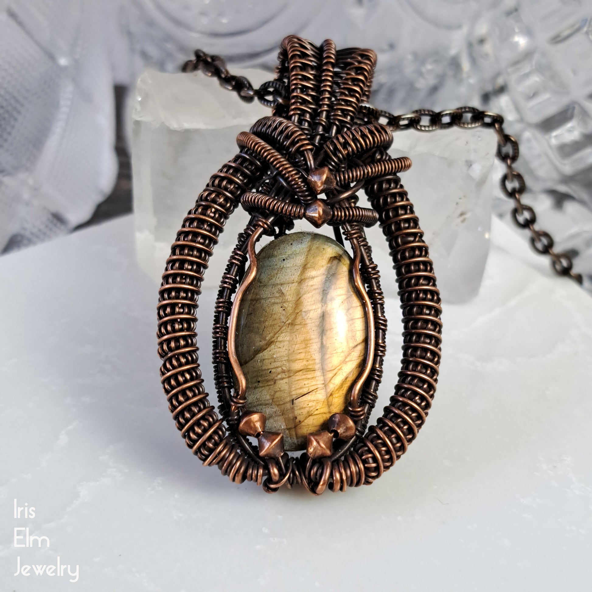 Jewelry with an iridescent labradorite stone and copper wire wrapping on a crystal background