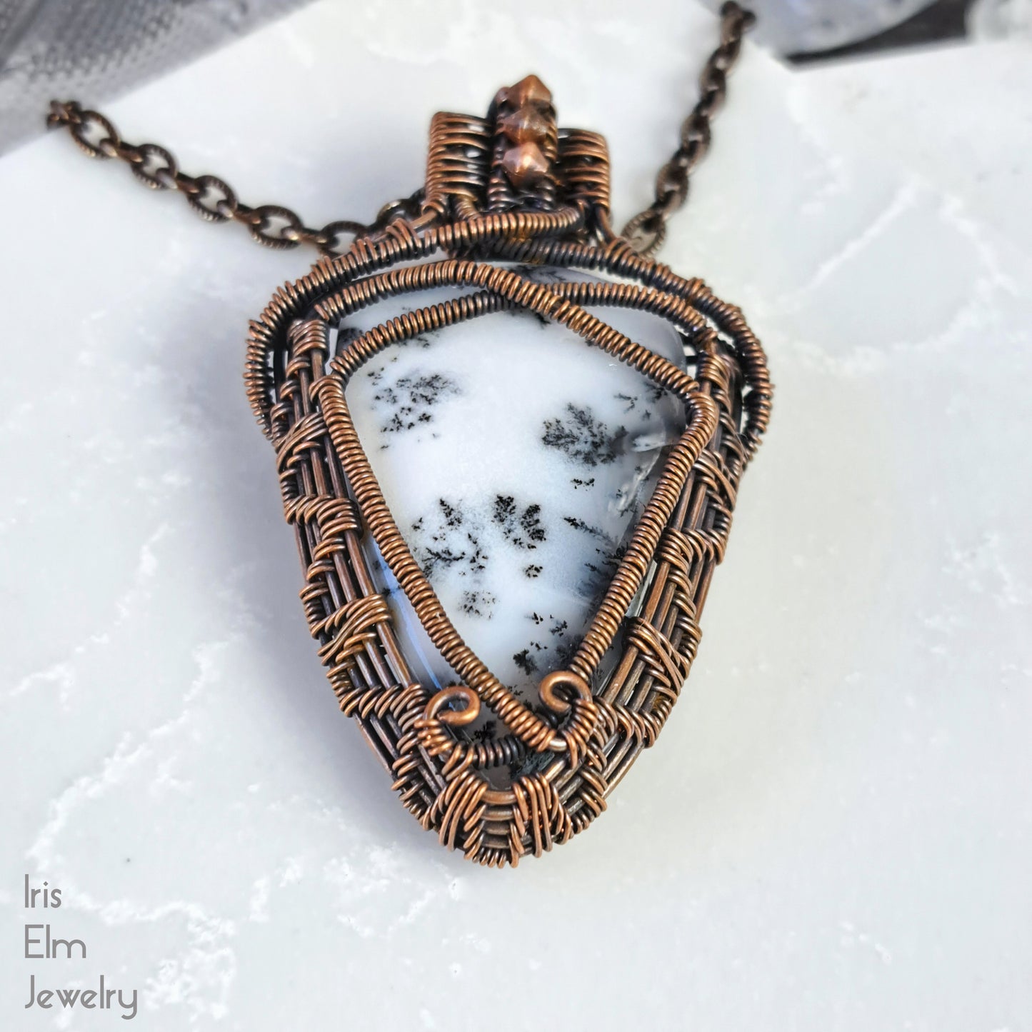 Jewelry pendant with white stone and woven copper wire on a white background