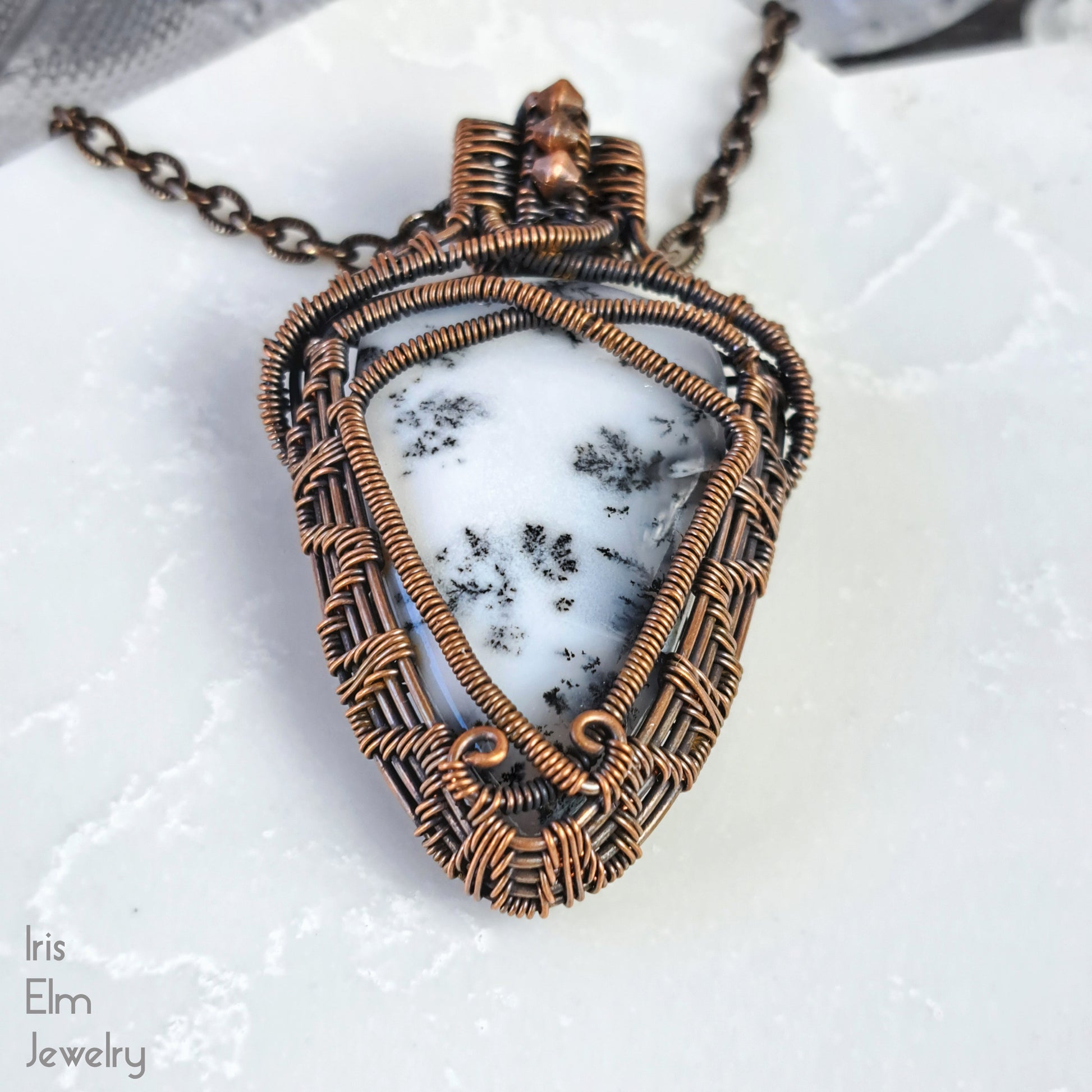 Jewelry pendant with white stone and woven copper wire on a white background