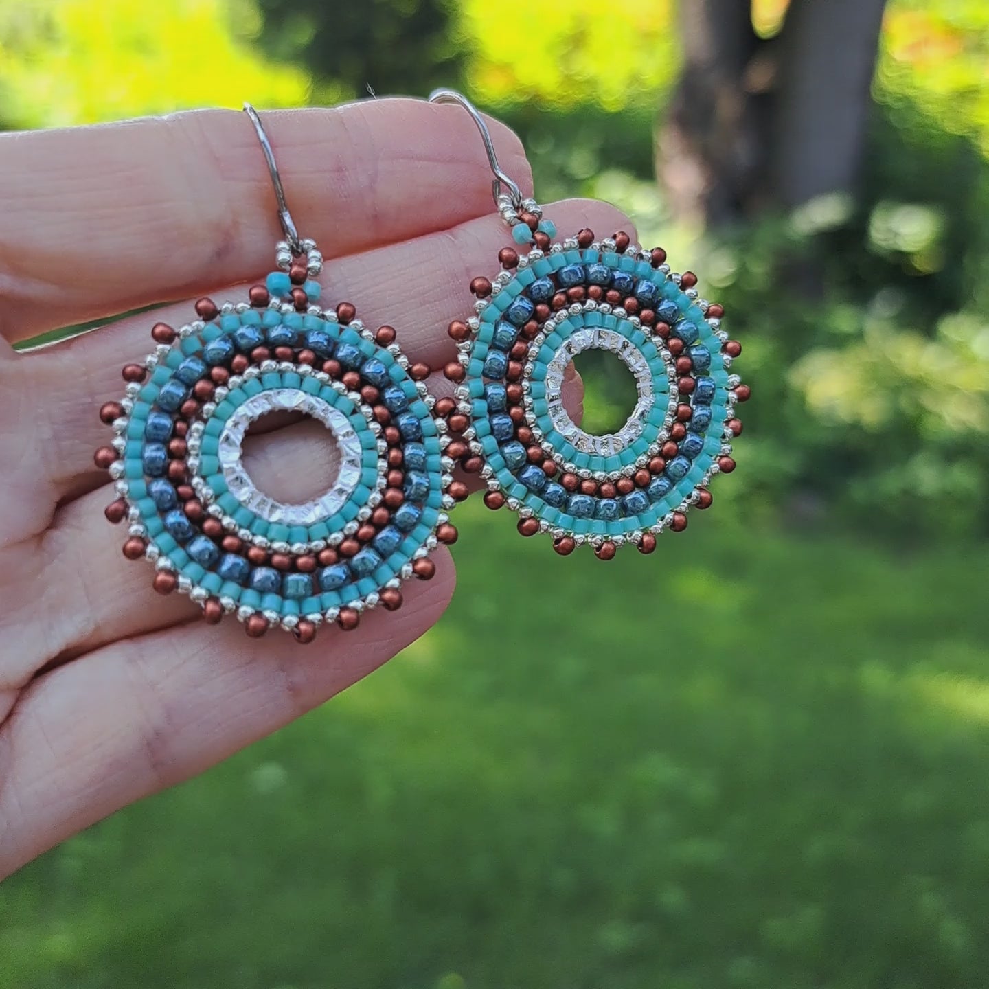hand holding pair of beadwork turquoise and burnt orange copper seed bead hoop earrings