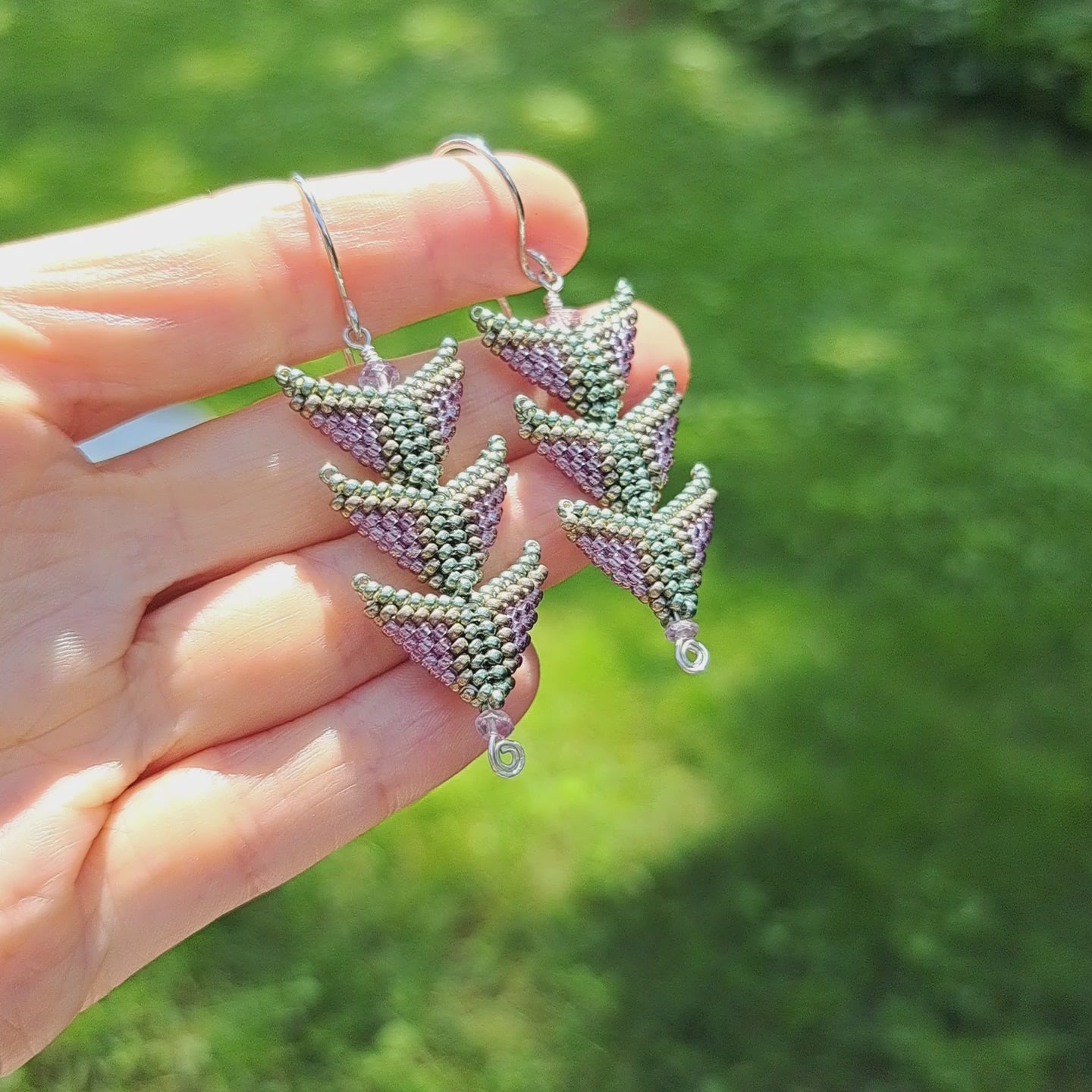 hand holding pair of purple and green seed bead three tiered triangle earrings with amethyst gemstones