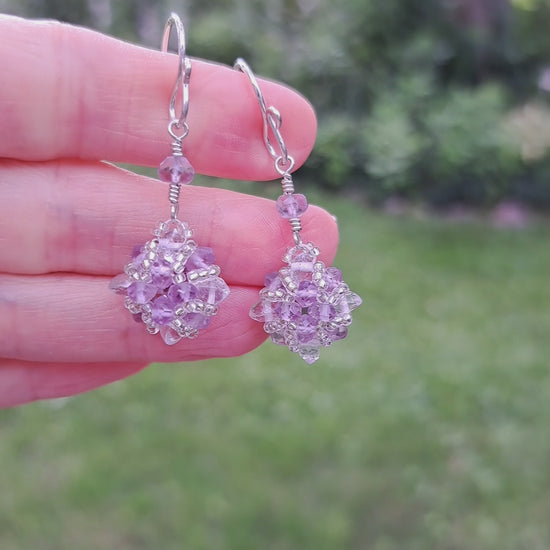 a pair of sterling silver beadwork gemstone purple amethyst and clear quartz crystal earrings held by hand