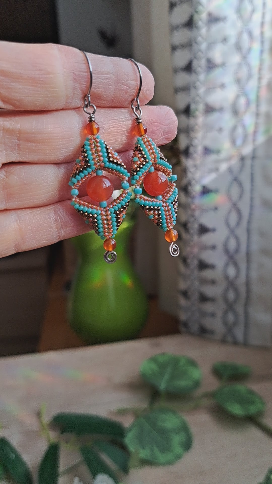 hand holding carnelian gemstone and seed bead beadwork earrings