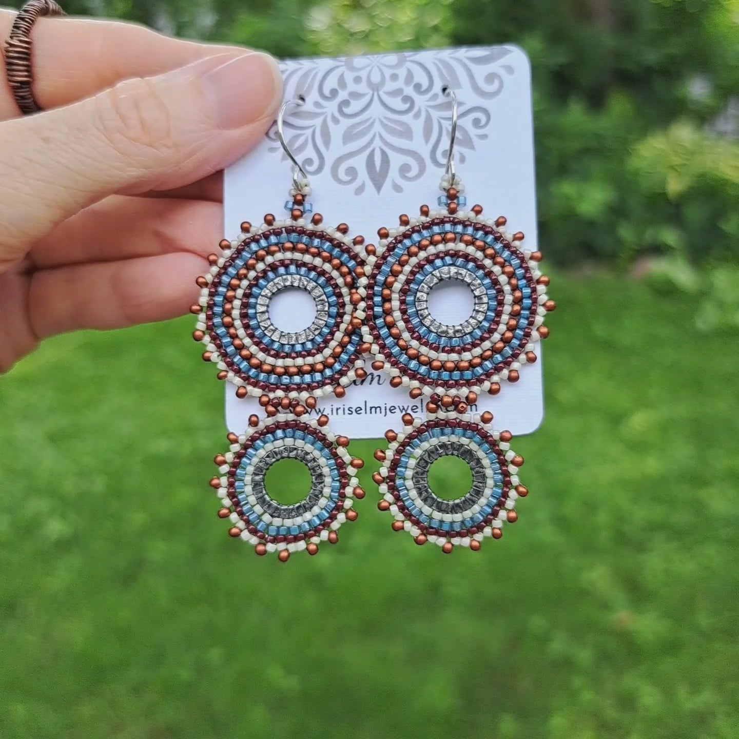 a pair of handwoven double hoop earrings on a Iris Elm Jewelry card held by hand