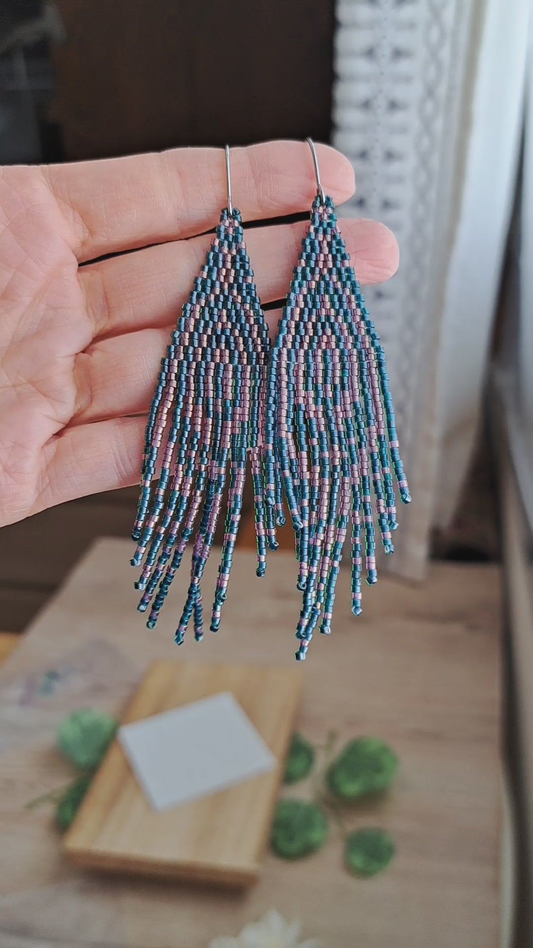hand holding pair of forest green and pink seed bead fringe art deco earrings