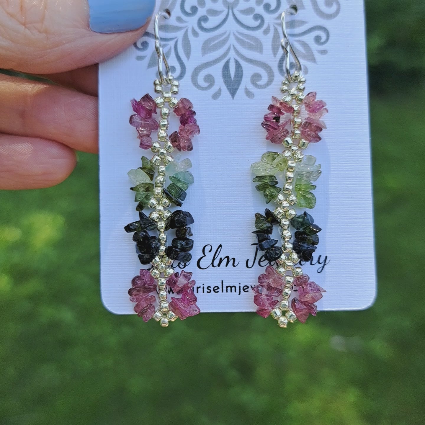a pair of pink and green rainbow tourmaline earrings on Iris Elm Jewelry card held by hand