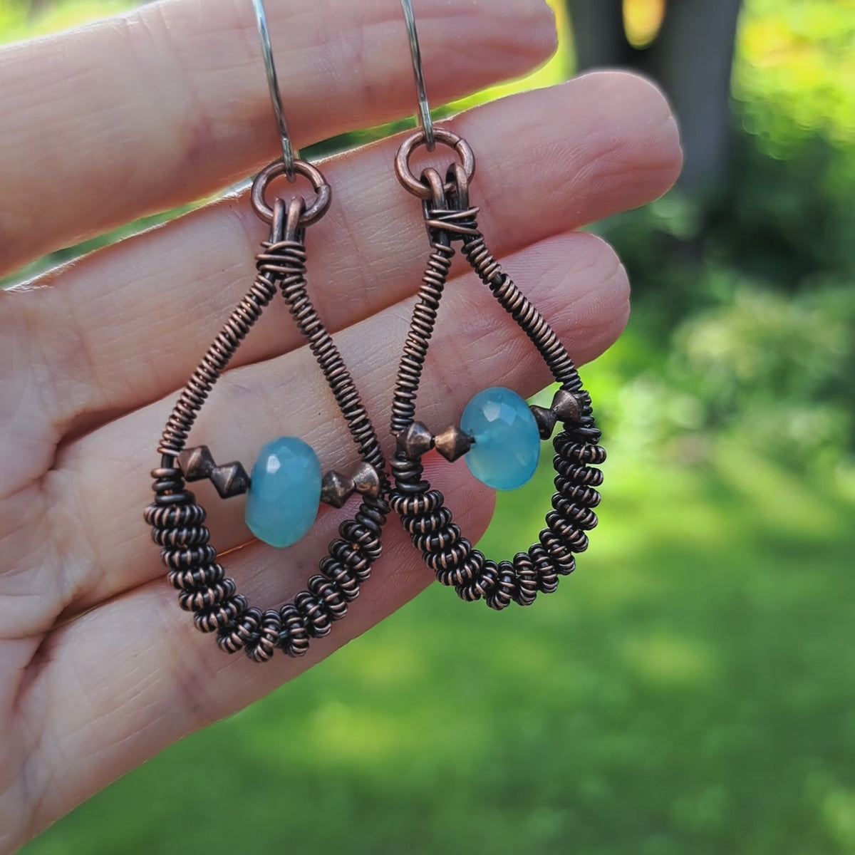 hand holding copper wire wrapped blue chalcedony handmade earrings