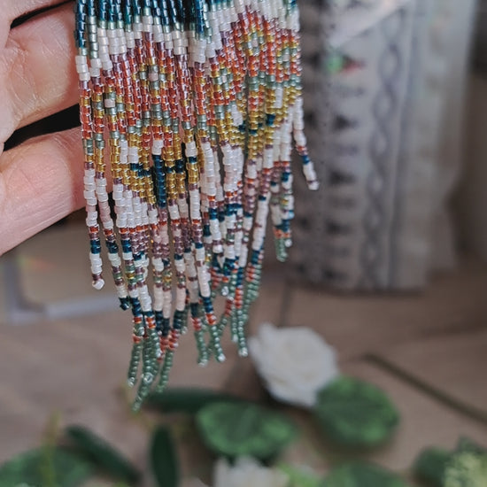 hand holding green, orange, yellow, pink spring floral folk art seed bead fringe earrings