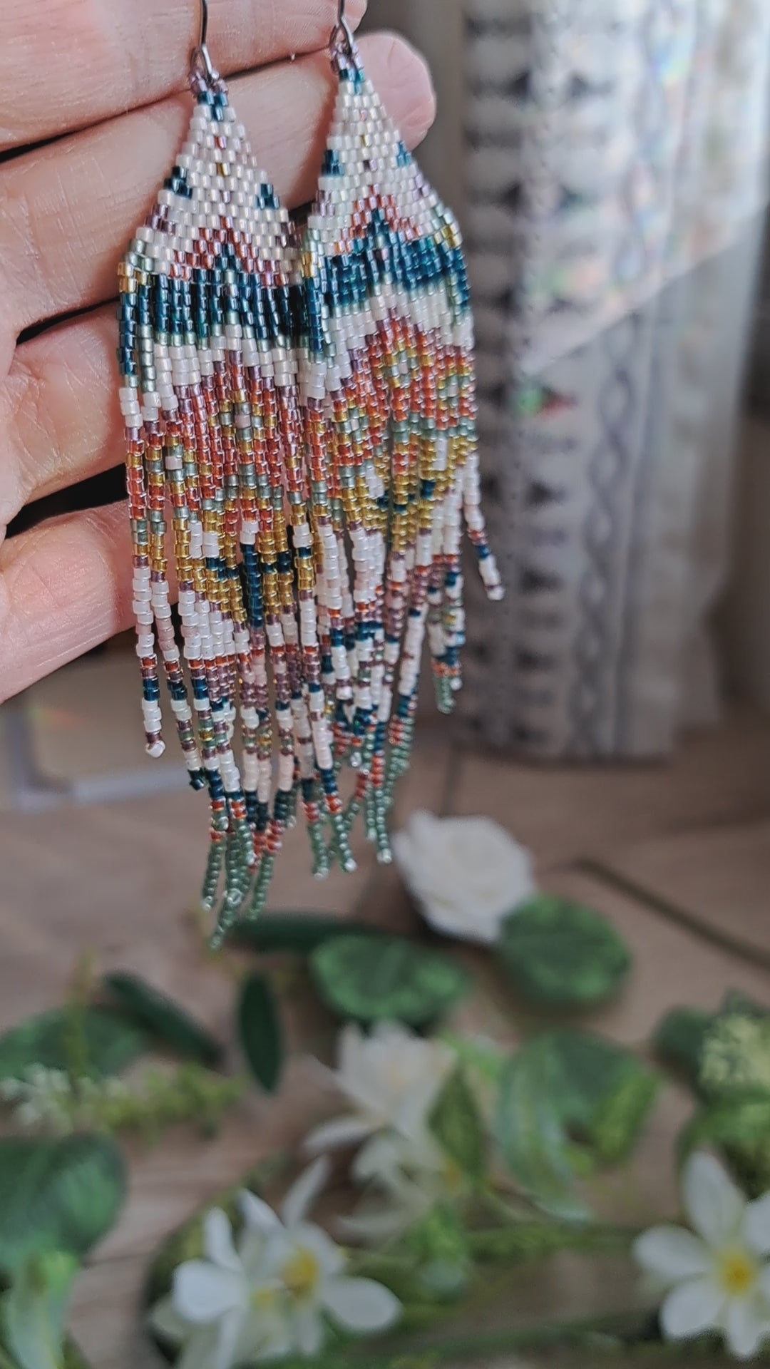 hand holding green, orange, yellow, pink spring floral folk art seed bead fringe earrings